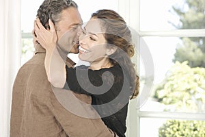 Mature couple hugging in living room.