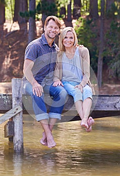 Mature couple, lake and sitting on dock, countryside and commitment with love in marriage. Happiness, smile and hug by