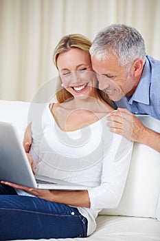 Mature couple, laptop and video call with embrace, conversation and living room couch. Social media, technology and