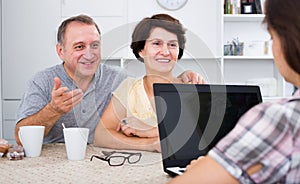 Mature couple listening to woman with laptop