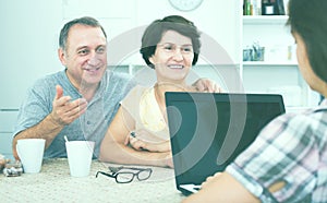 Mature couple listening to woman with laptop