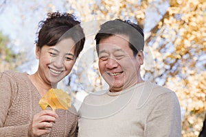 Mature Couple Looking at the Leaf and Smiling in the Park in Autumn