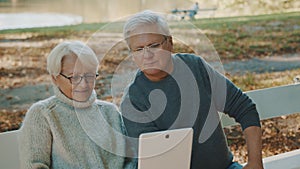 Mature couple in love taking selfie in forest on autumn day. Video call or browsing old photos