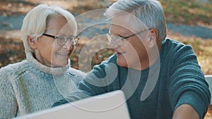 Mature couple in love taking selfie in forest on autumn day. Video call or browsing old photos