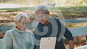 Mature couple in love taking selfie in forest on autumn day. Video call or browsing old photos