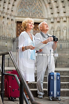 Mature couple making photo and using map during joint vacation