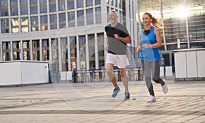 Mature couple, man and woman exercising and jogging together in the city on a warm summer day