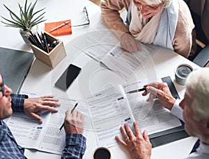 A mature couple meeting with a financial advisor to discuss retirement plans from above. A senior couple meeting a