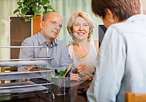 Mature couple of pensioners talking with employee
