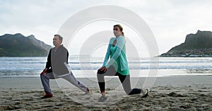 Mature couple performing stretching exercise on beach