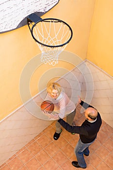 Mature couple playing basketball in patio