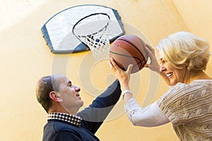 Mature couple playing basketball in patio