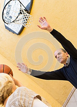 Mature couple playing basketball in patio