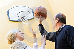 Mature couple playing basketball in patio