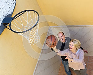 Mature couple playing basketball in patio