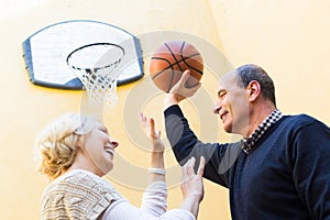 Mature couple playing basketball in patio