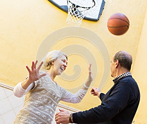 Mature couple playing basketball in patio