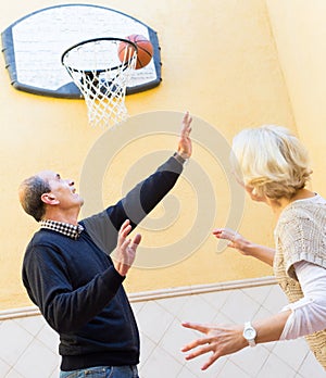 Mature couple playing basketball in patio