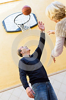 Mature couple playing basketball in patio