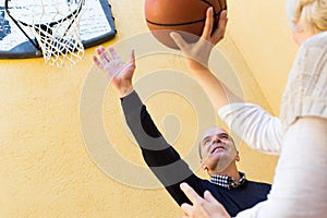 Mature couple playing basketball in patio