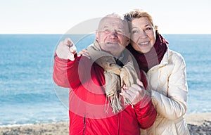 Mature couple pointing on beach