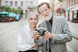 Mature couple posing outdoors with retro photo camera
