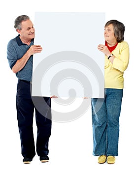 Mature couple presenting blank white billboard