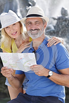 Mature couple reading map sightseeing joyful smiling outdoors