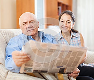 Mature couple reading newspaper together