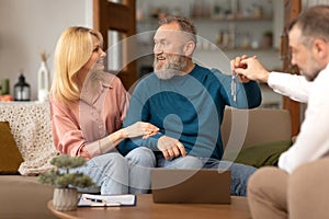 Mature Couple Receiving House Keys From Real Estate Agent Indoor