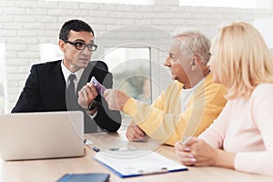 Mature couple at a reception with a lawyer. The old man and the lawyer are holding a bundle of money.