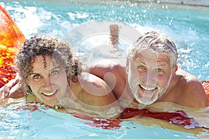 Mature Couple Relaxing On Airbed In Swimming Pool photo