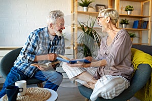 Mature couple relaxing at home and reading book together