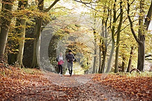 Mature Couple Running Through Autumn Woodland Together