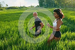 Mature Couple Running On Rice Field In Morning. Caucasian Man And Asian Woman On Jogging Workout.