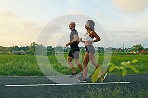 Mature Couple Running On Road At Tropical Landscape. Caucasian Man And Asian Woman On Jogging Workout.