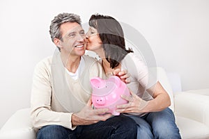 Mature couple saving money in piggybank