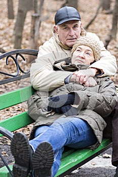 A mature couple is sitting on a bench