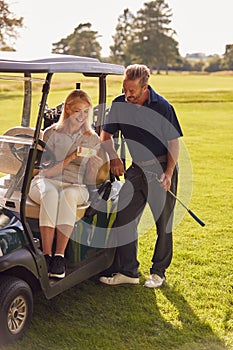 Mature Couple Sitting In Buggy Playing Round On Golf And Checking Score Card Together