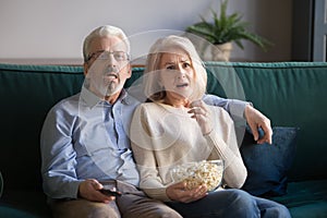 Mature couple sitting on couch watching drama movie