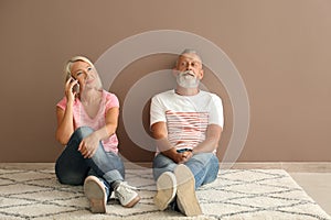 Mature couple sitting on floor in empty room. Moving into new house