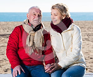 Mature couple sitting by sea