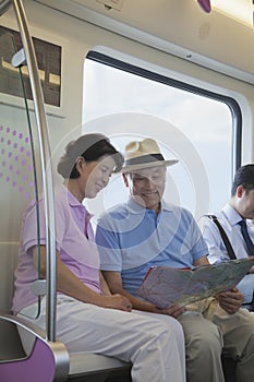 Mature couple sitting in the subway and looking at the map