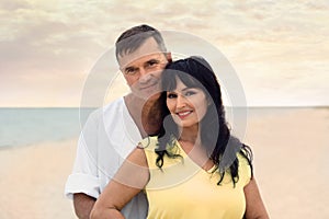 mature couple spending time together on sea beach at sunset