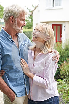 Mature Couple Standing In Garden In Front Of Dream Home In Countryside