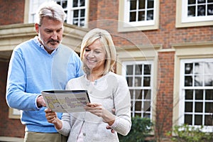 Mature Couple Standing Outside House Looking At Property Details photo