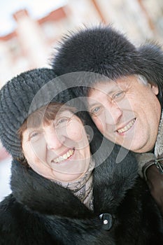 Mature couple on  street in winter near multistory houses