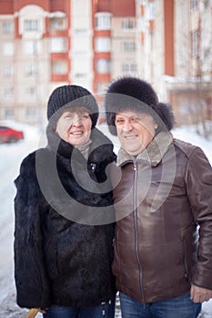 Mature couple on  street in winter near multistory houses