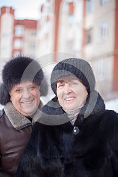 Mature couple on  street in winter near multistory houses