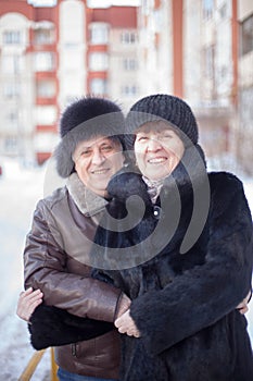 Mature couple on  street in winter near multistory houses